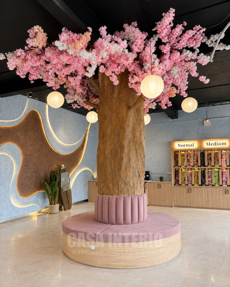 Cherry blossom tree with paper lanterns rising from a round velvet bench