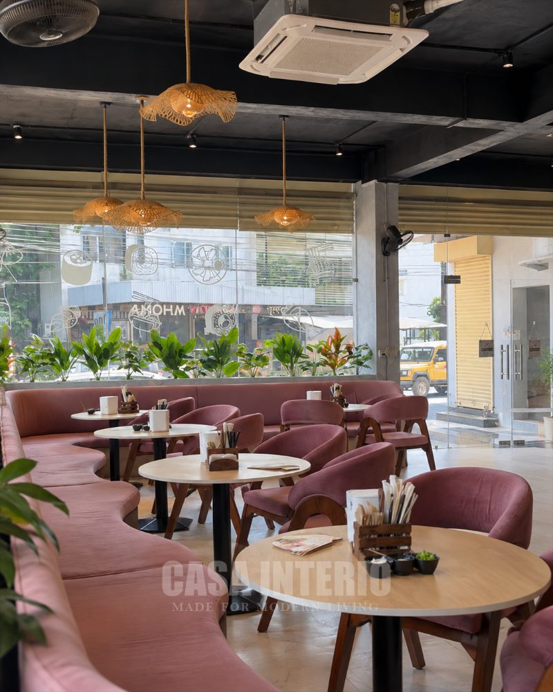 Curved rose banquette and round tables under rattan pendants